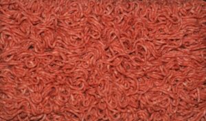 Carne macinata in vaschetta con colore grigio sul fondo, avviso per un acquisto consapevole.